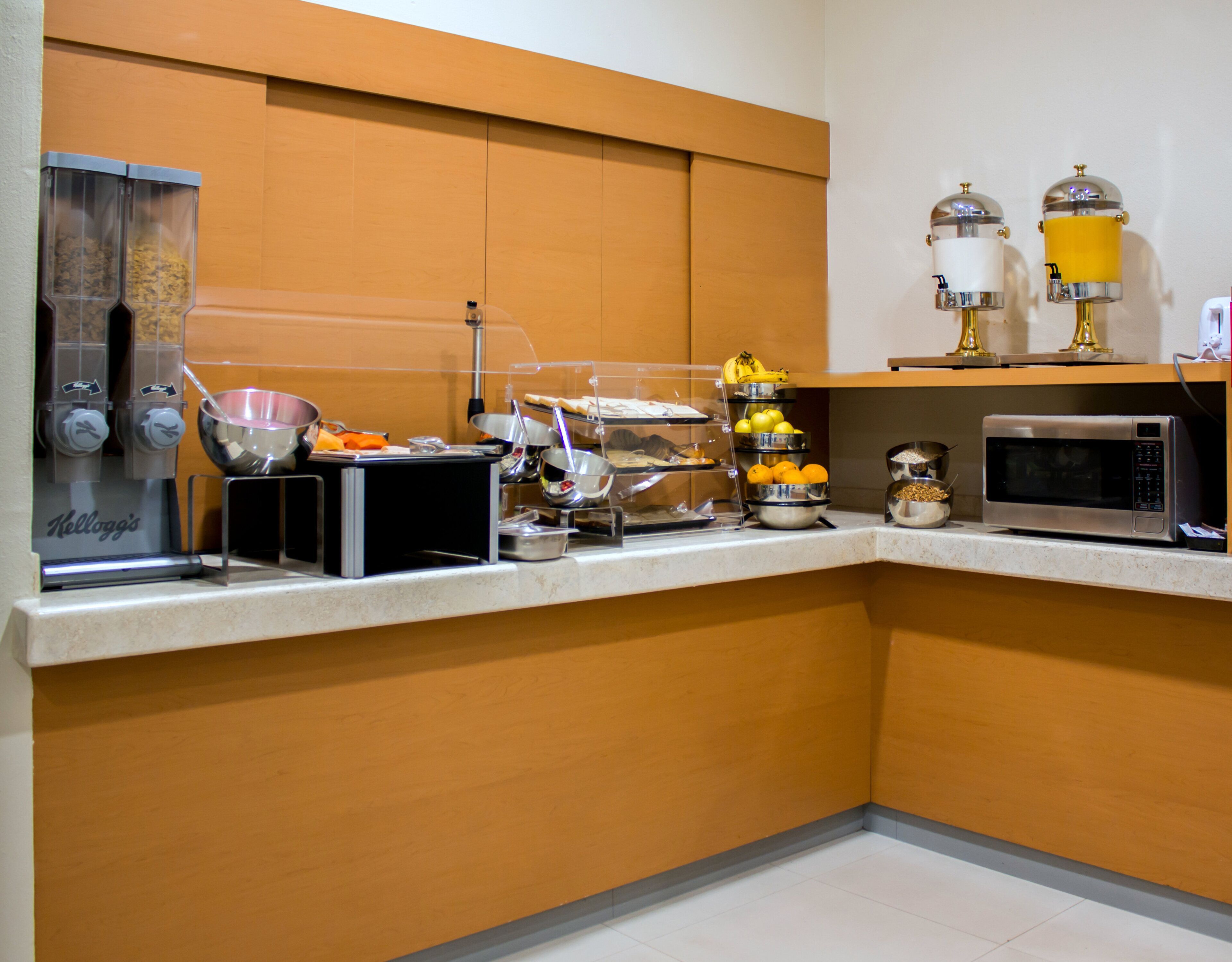 A kitchenette with a coffee machine, microwave, and various food containers.