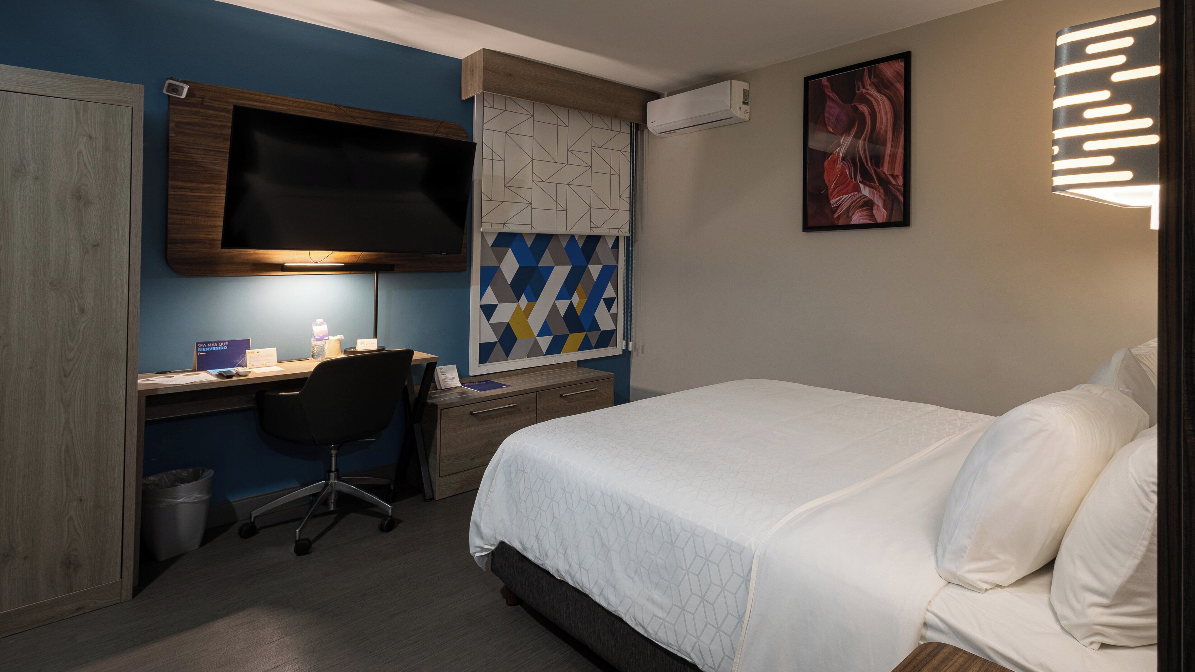 Una habitación de hotel con cama, escritorio, silla y televisión.