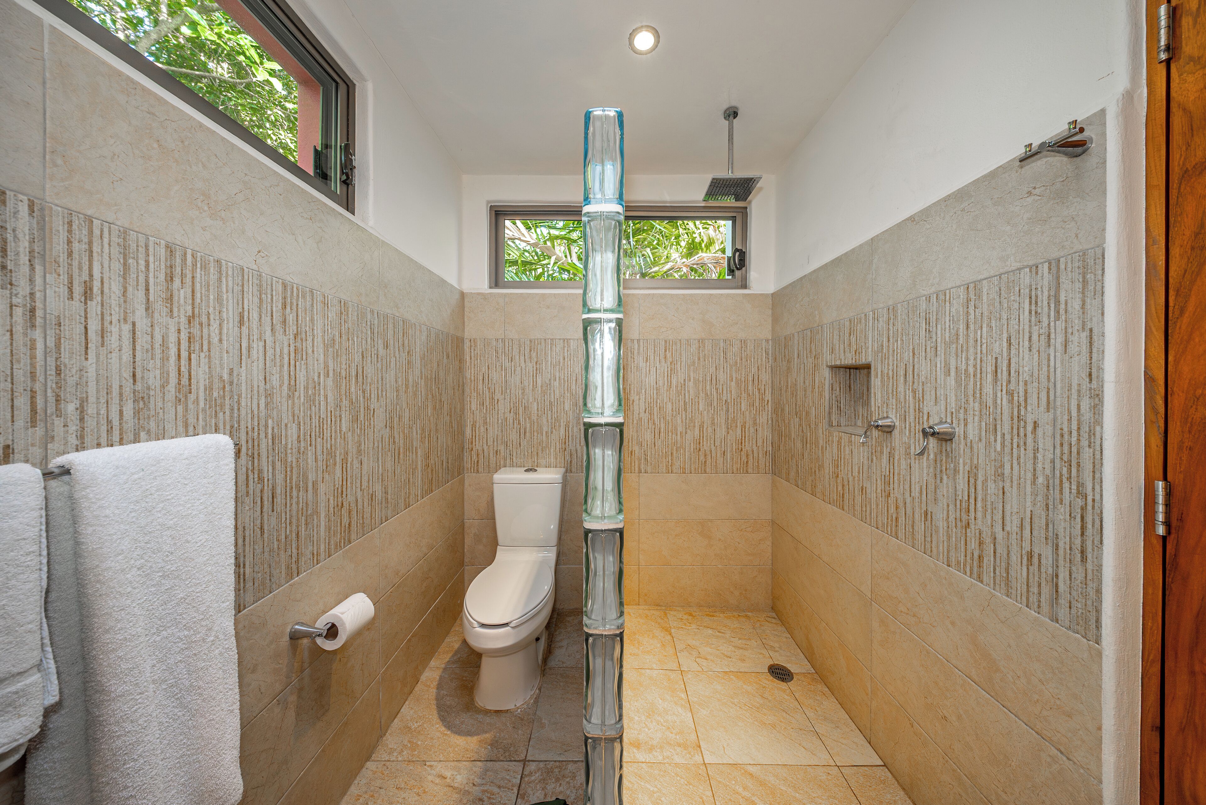 Une salle de bain équipée de toilettes, d’une colonne de douche en verre et d’un porte-serviettes.
