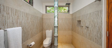 Une salle de bain équipée de toilettes, d’une colonne de douche en verre et d’un porte-serviettes.