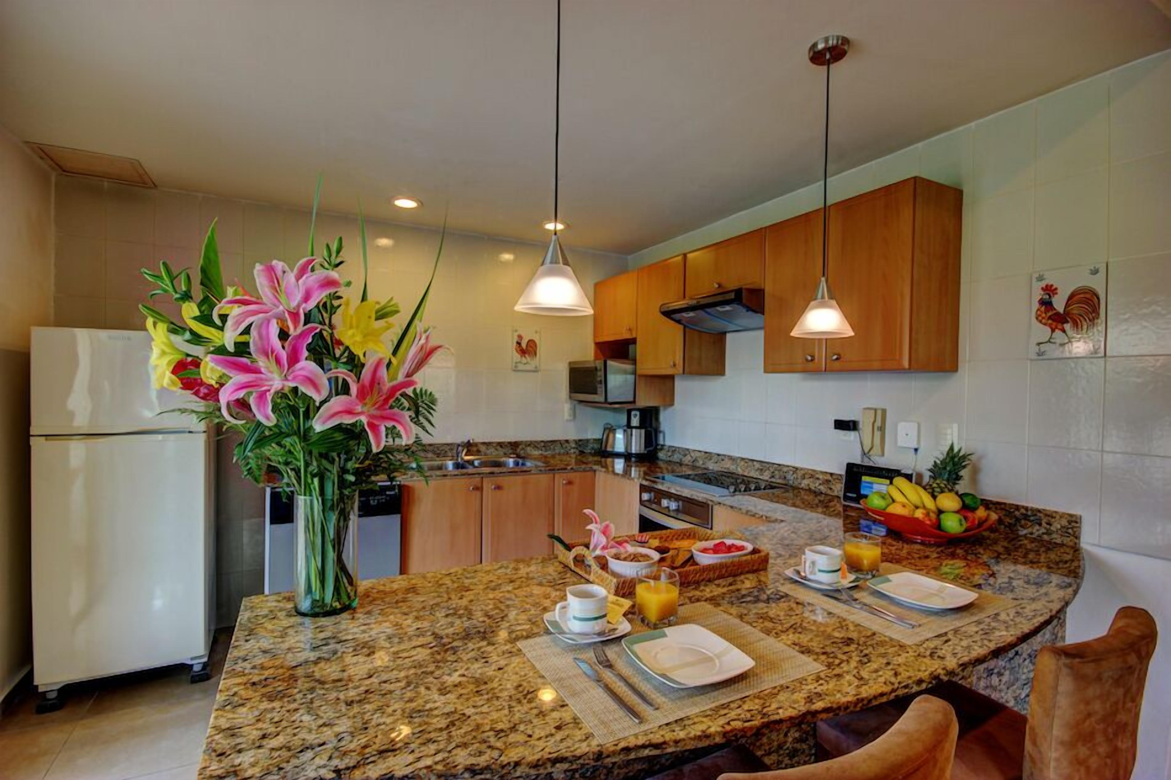 A modern kitchen with granite countertops, wooden cabinets, and pendant lighting.