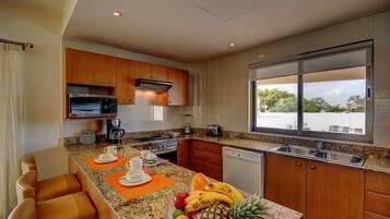A modern kitchen with granite countertops, wooden cabinets, and a large window offering a view of the outdoors.