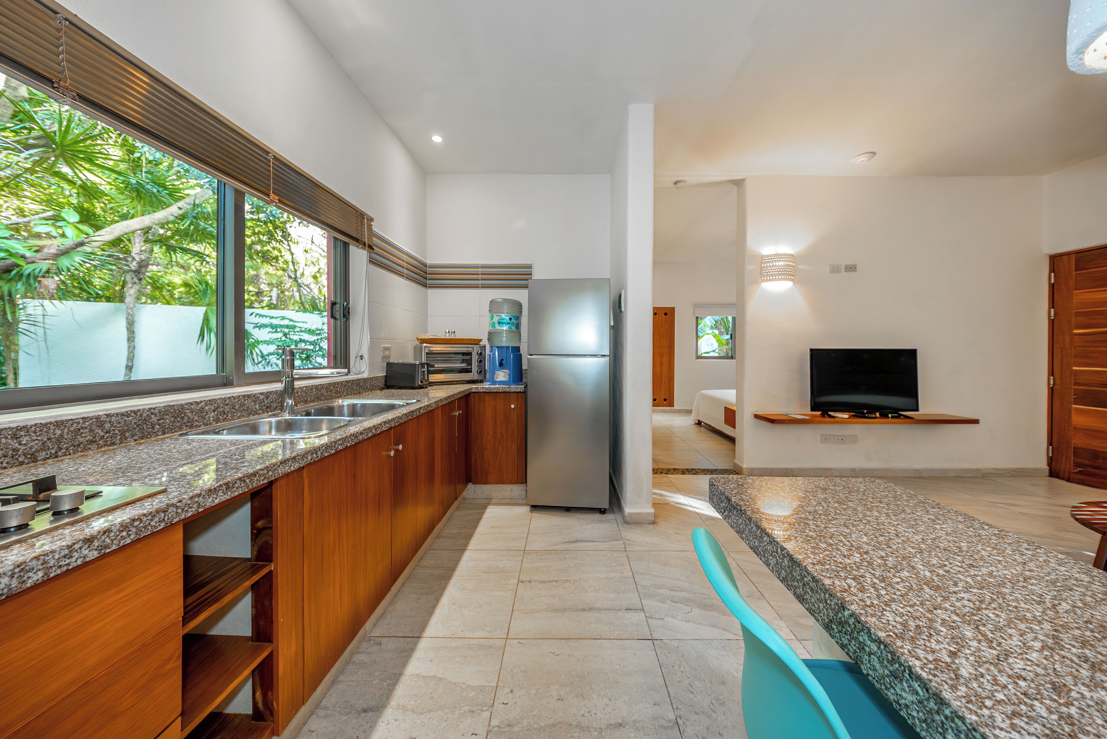 Una cocina moderna con encimeras de granito, armarios de madera, refrigerador de acero inoxidable y horno empotrado.
