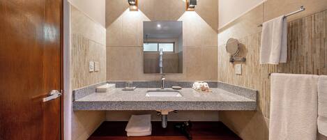 A bathroom with a wooden door, a granite countertop sink, a towel rack, and a mirror.