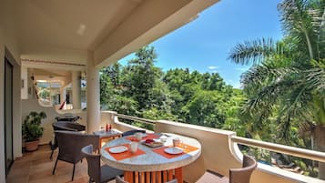 Een balkon met een ronde tafel en stoelen, omringd door potplanten.