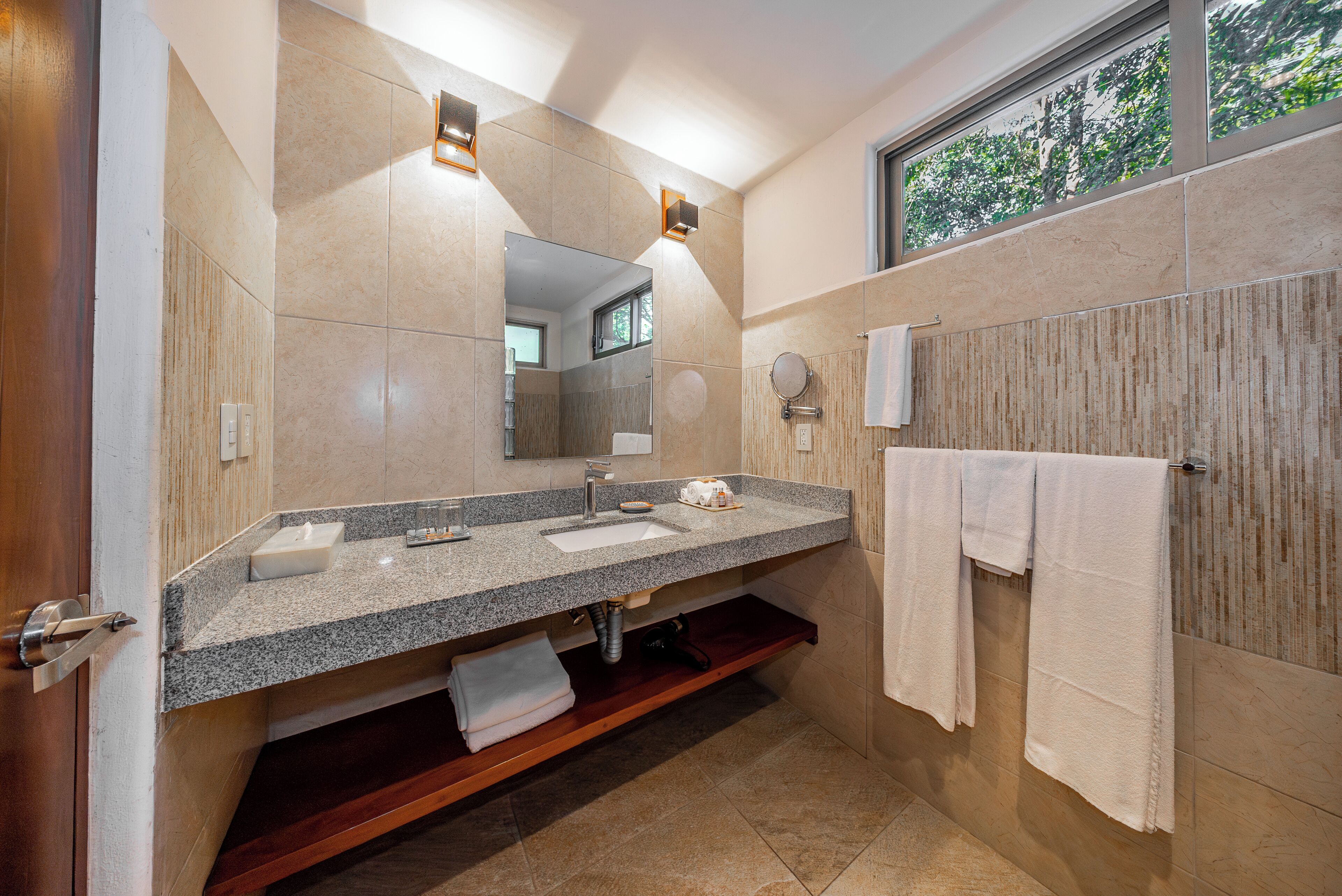 Un baño moderno con dos lavamanos, un espejo grande y una ventana.