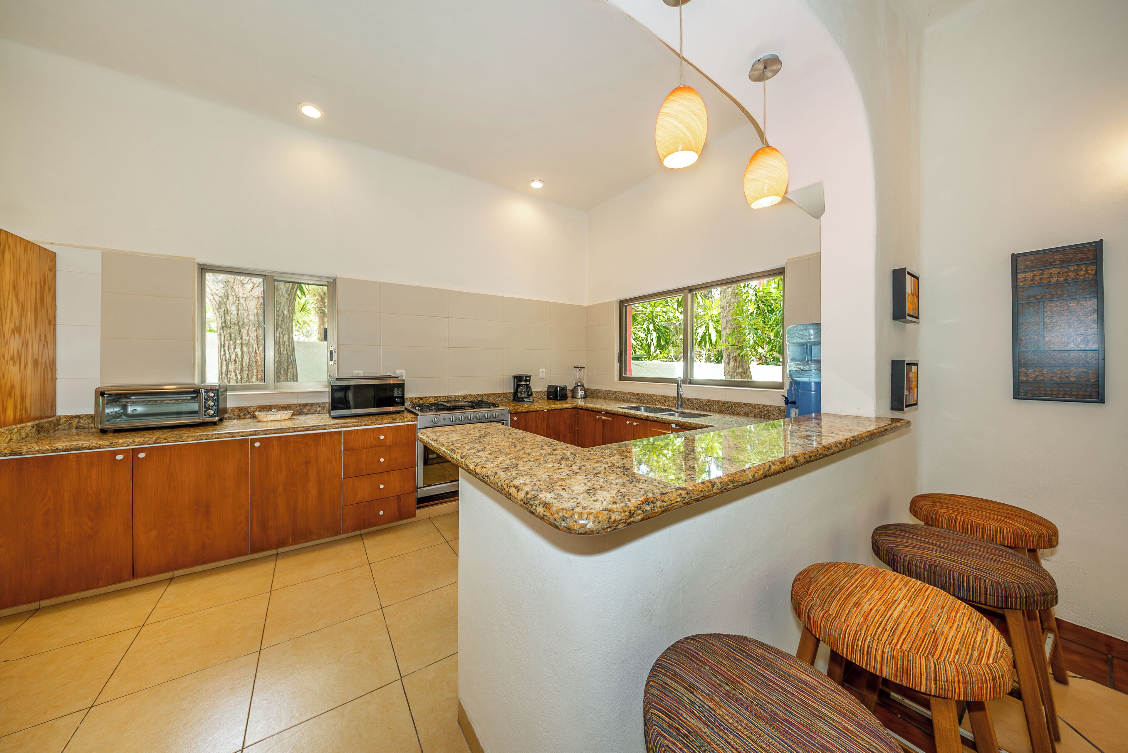 A modern kitchen with a large island, wooden cabinets, a microwave, and a toaster.