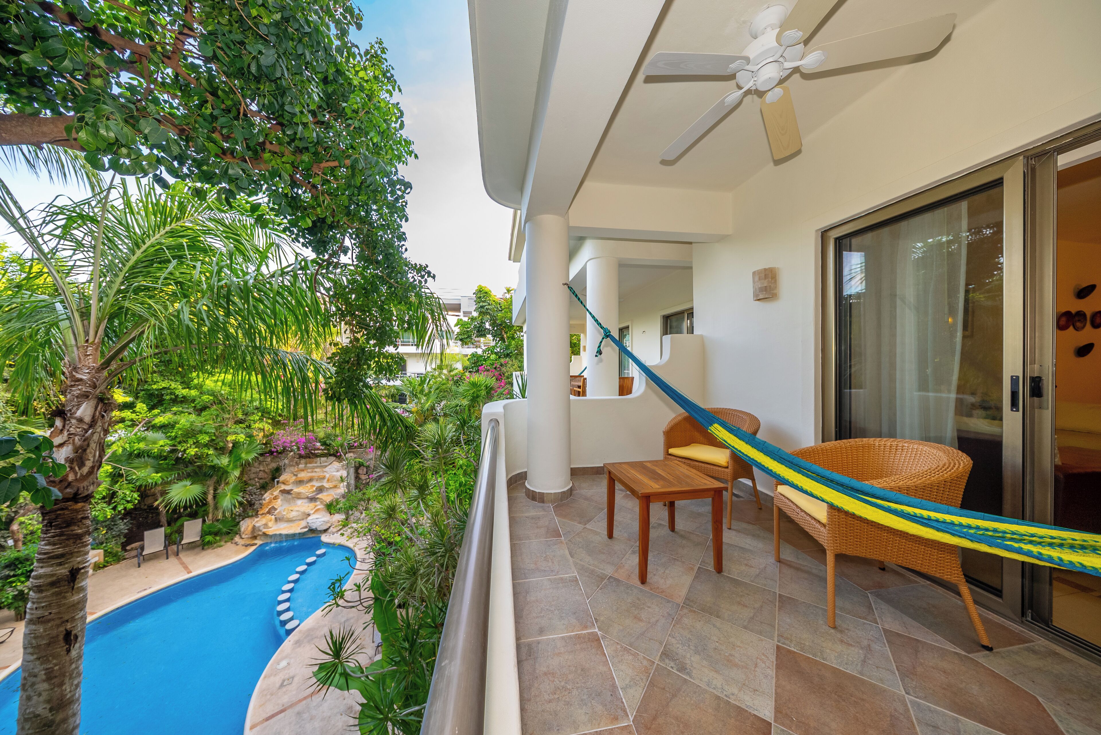 A balcony with a pool, a hammock, and a chair.