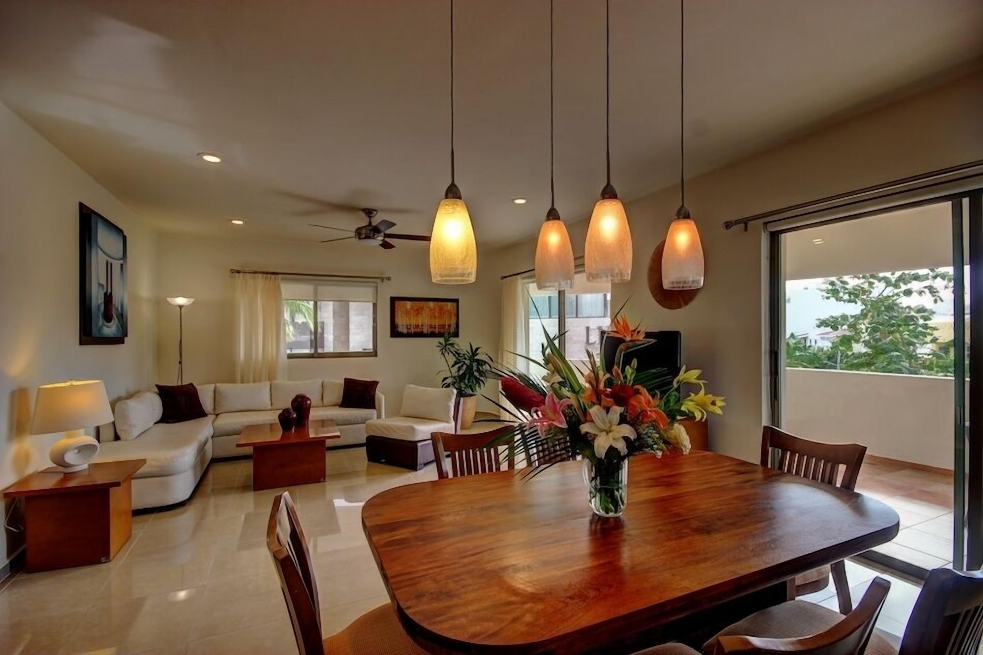 Uma sala de estar moderna com uma mesa de jantar, sofás e uma janela grande.