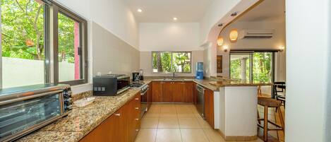 A modern kitchen with a built-in oven, a sink, and a bar area with stools.