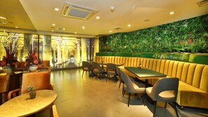 A restaurant with booths, round tables, and a green wall with plants. - All Seasons Hotel (Istanbul)