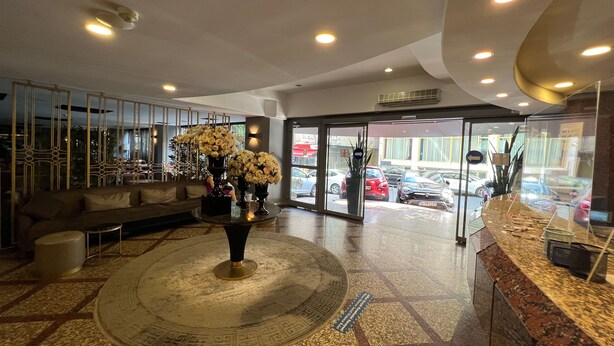 A lobby with a round carpeted area, a reception desk, and a seating area with a sofa. - All Seasons Hotel (Istanbul)