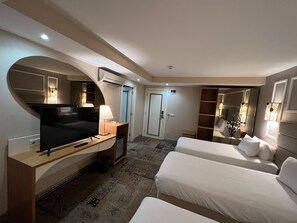 Ein Hotelzimmer mit Fernseher, Schreibtisch, Lampe und zwei Betten.