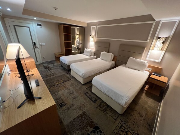 Ein Hotelzimmer mit zwei Betten, einem Schreibtisch mit Lampe, einem Kleiderschrank und einem kleinen Fenster.