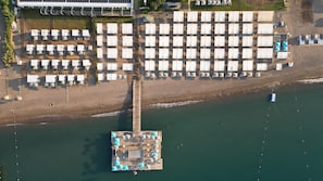 Aan een privéstrand, ligstoelen, parasols, beachvolleybal