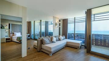 Una habitación de hotel moderna con una cama grande, un sofá, un comedor y un balcón con vistas.