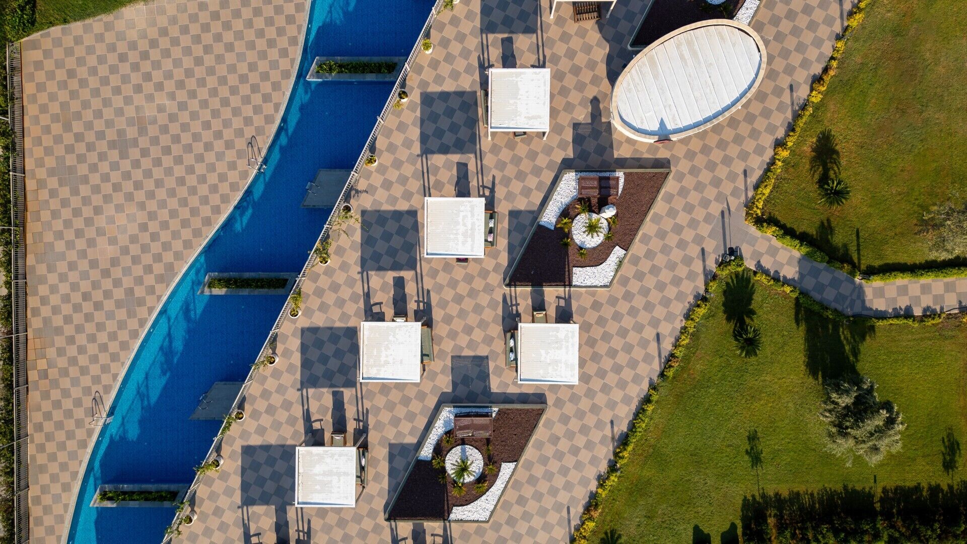 An aerial view of a pool area with checkered flooring, lounge chairs, and a circular seating area.