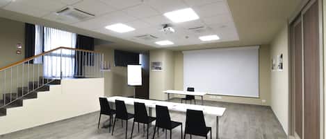 A conference room with a whiteboard, projector, and a long table with chairs.