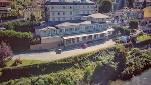 A multi-story hotel with a flat roof, a parking lot, and a river in the foreground.