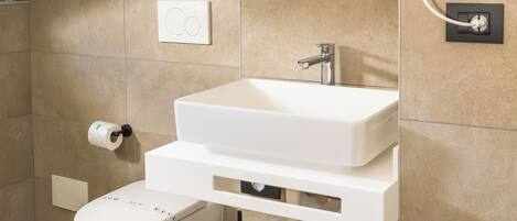 A modern bathroom with a white sink, a toilet, and a mirror above the sink.