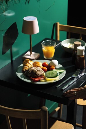 A breakfast table with croissants, tomatoes, cucumbers, a plate of bread, a glass of orange juice, and condiments. - Qbic Hotel Amsterdam WTC (Amsterdam)