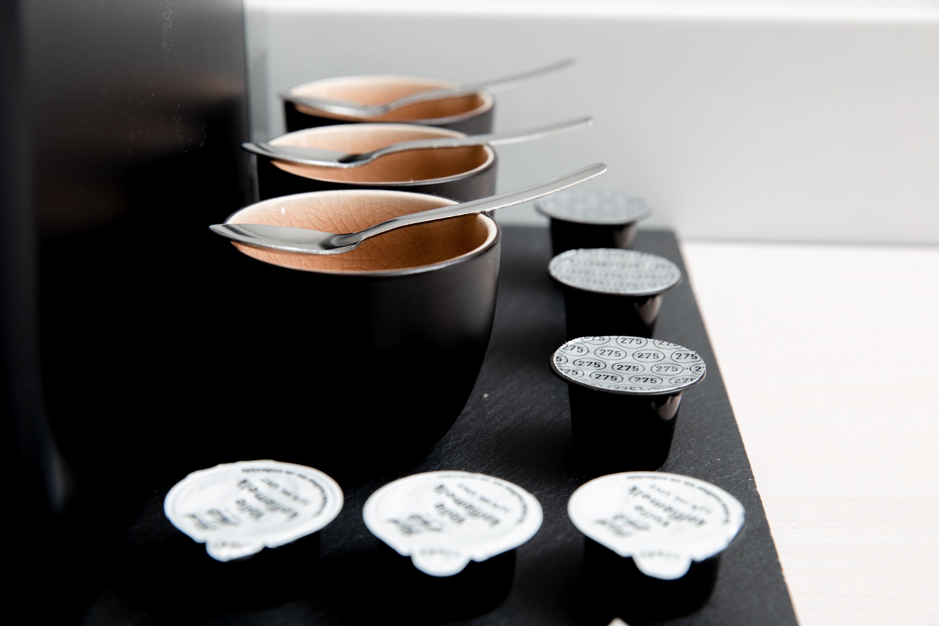 A row of black containers with spoons and labels.
