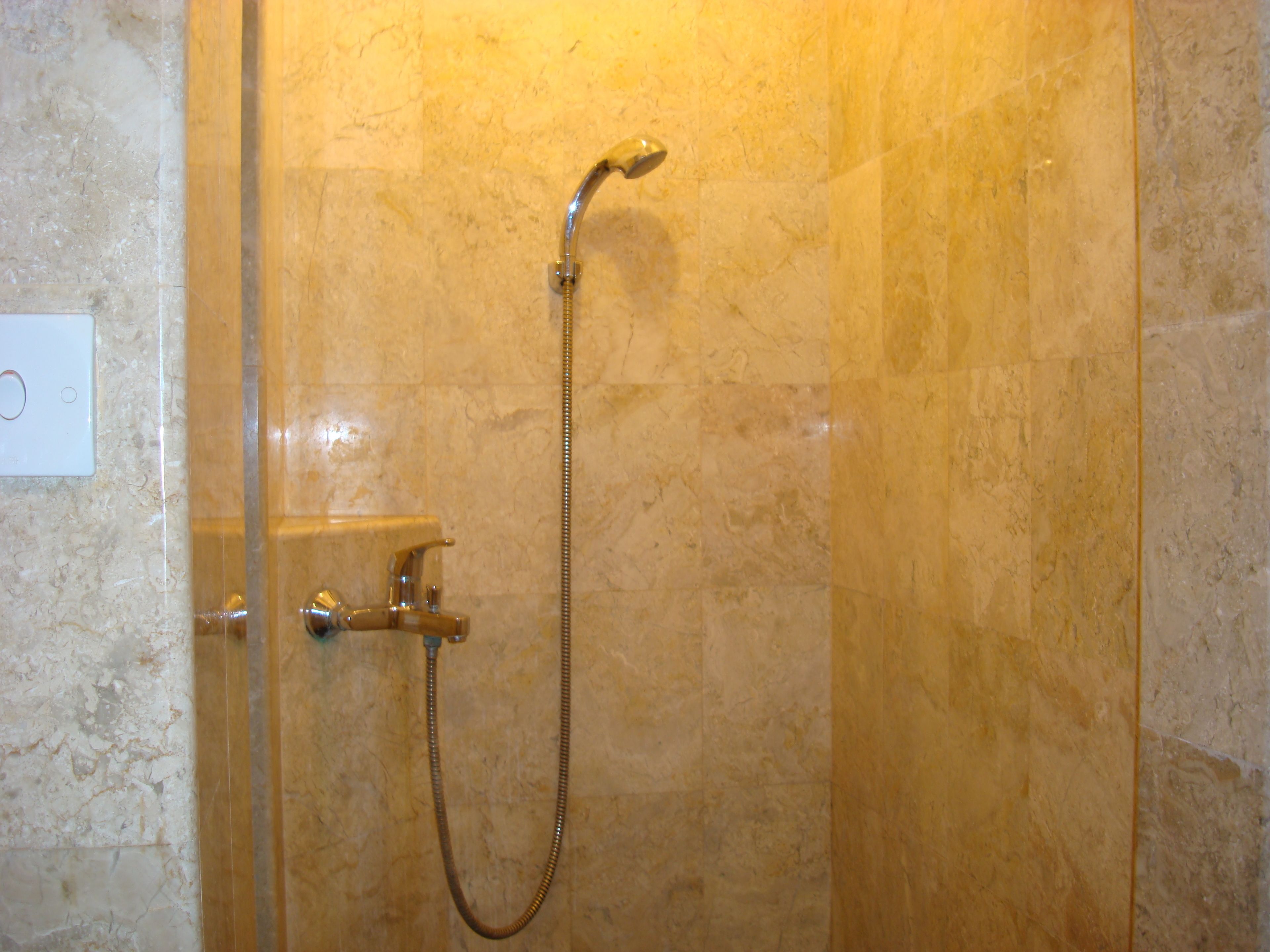A shower with a handheld showerhead and a wall-mounted faucet.