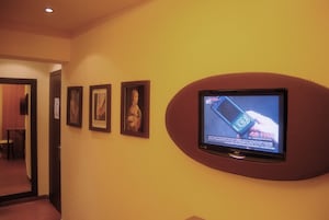 Un pasillo con cuadros en la pared y un televisor mostrando un anuncio de teléfono móvil.