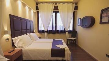 Een hotelkamer met een bed, een stoel, een televisie en gordijnen.