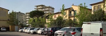 Una hilera de coches aparcados en una calle residencial con edificios altos al fondo.