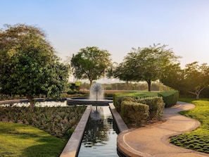 Un jardin aménagé avec un élément aquatique central, un chemin sinueux et des haies soigneusement taillées.