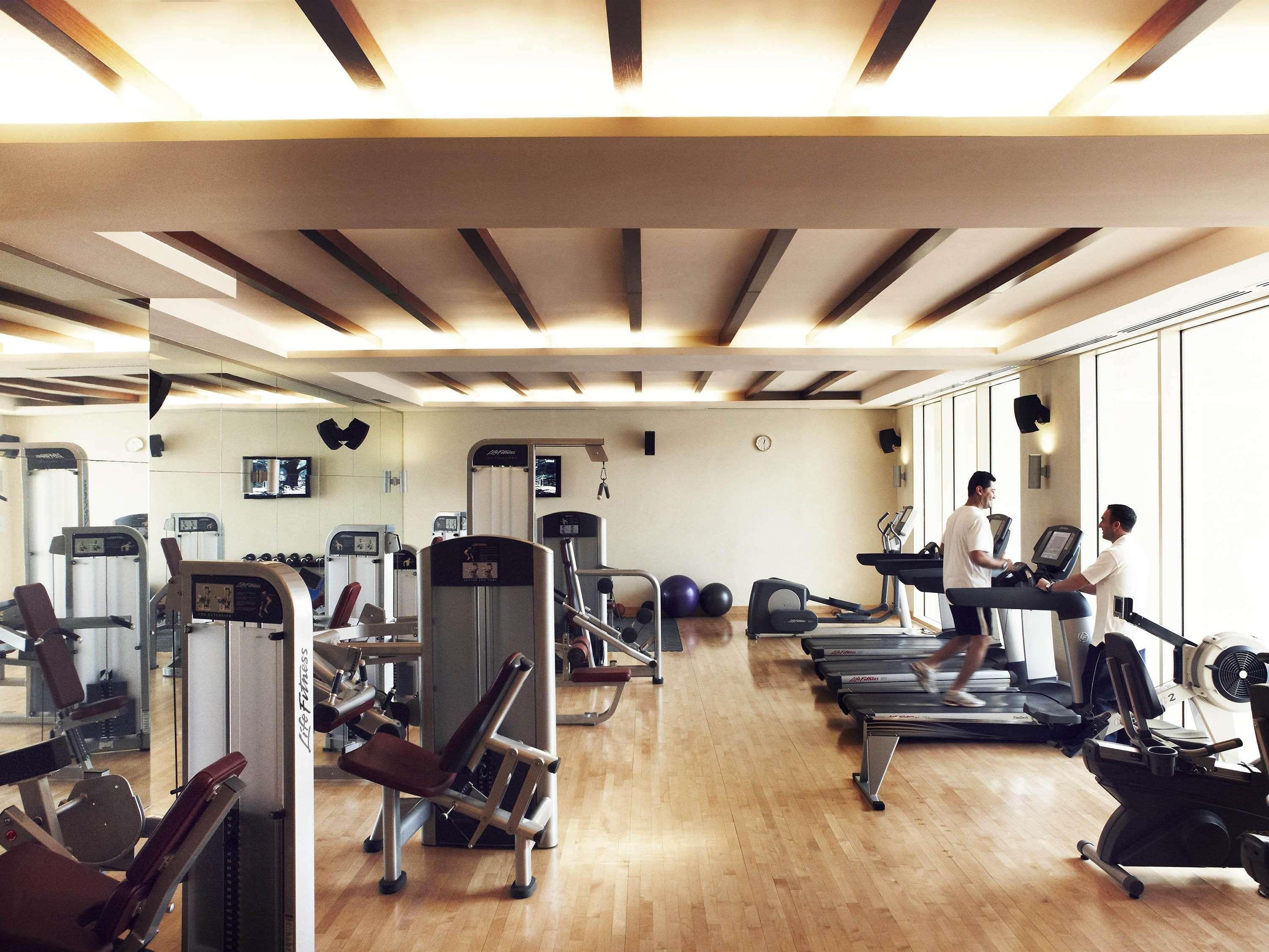 Une salle de sport équipée de tapis de course, d’appareils de musculation et de ballons d’exercice.