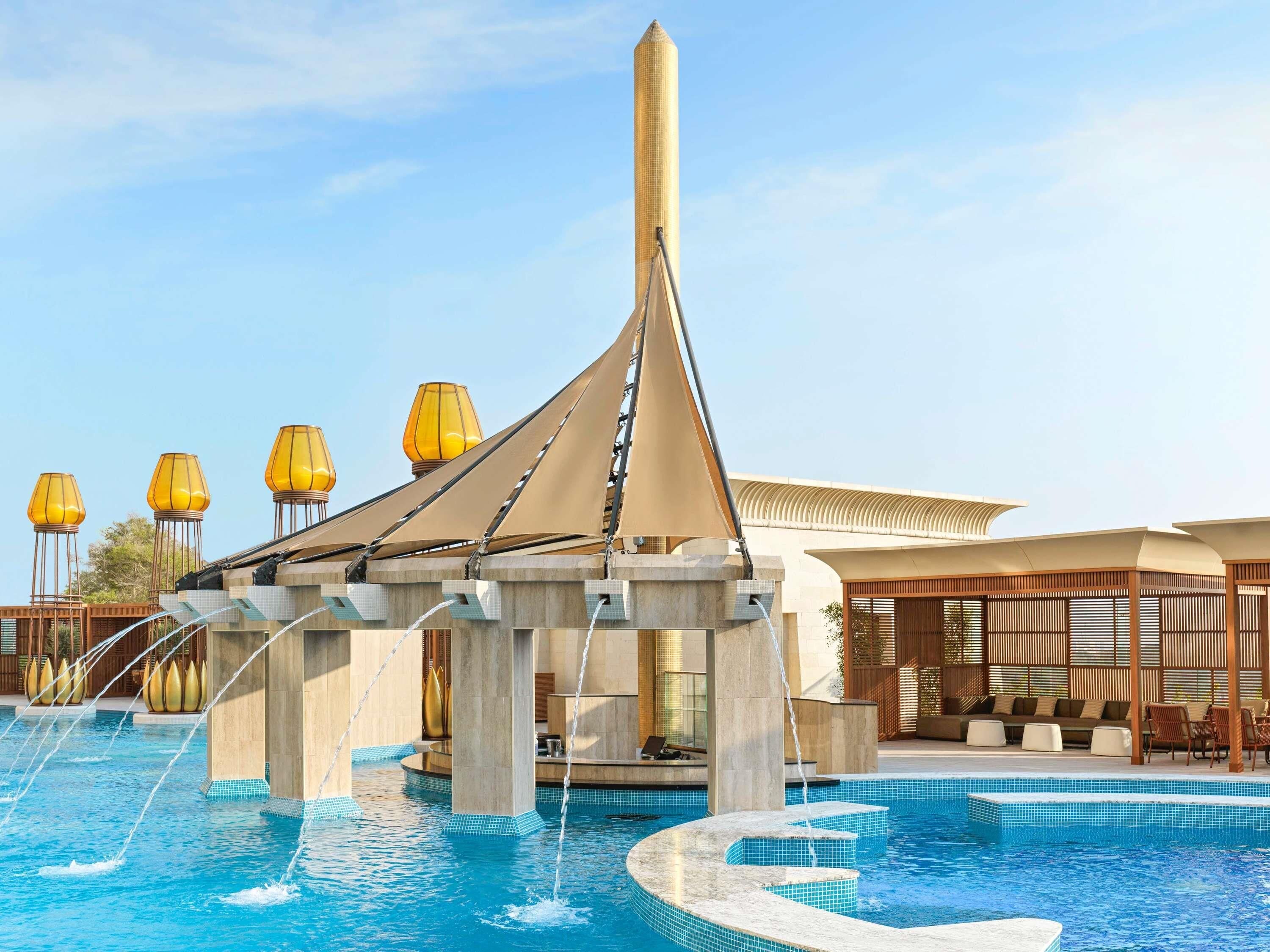 Uma área de piscina com design moderno, incluindo uma estrutura única com telhado inclinado e um pilar central.