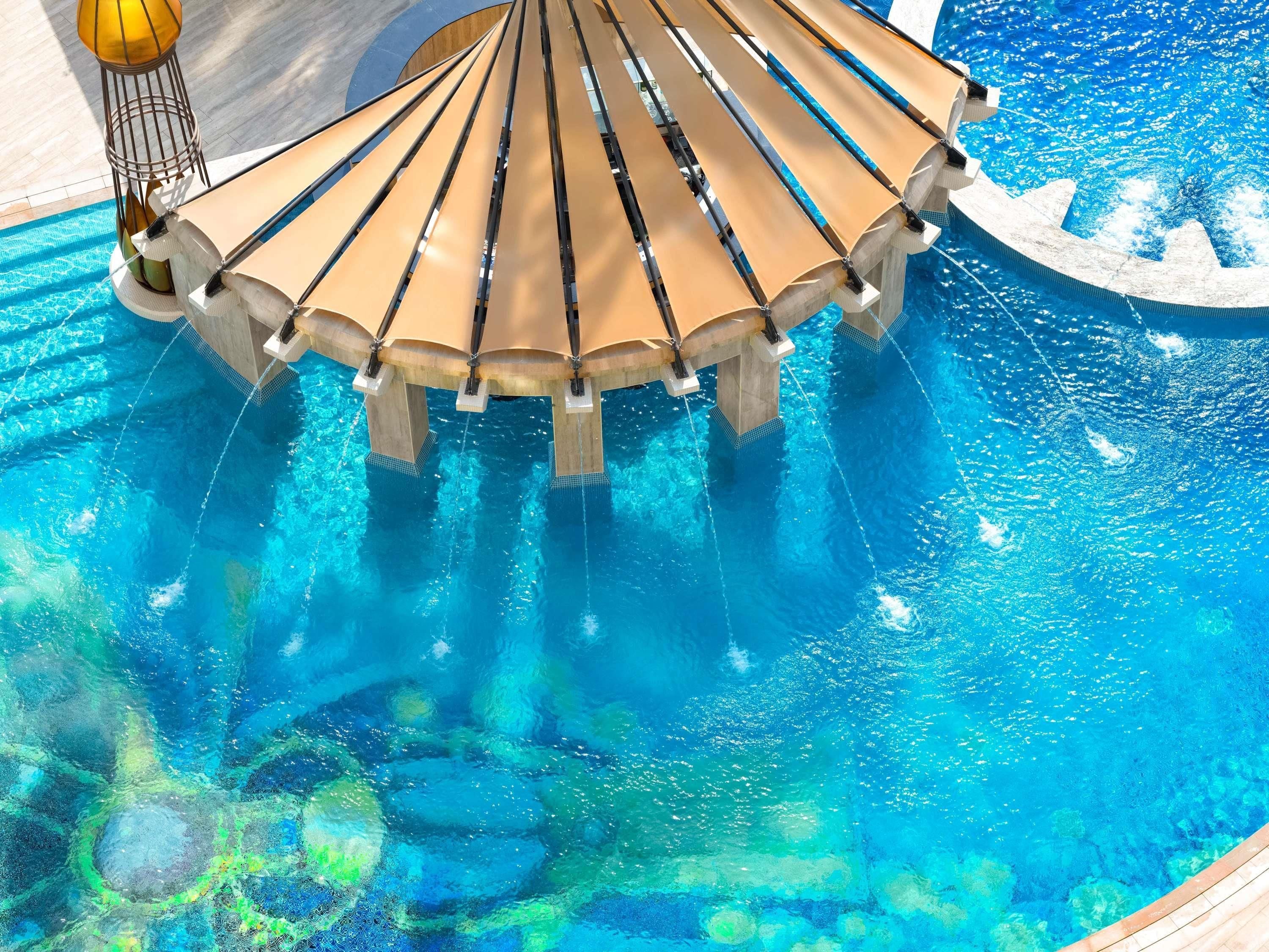 Una piscina con una estructura de sombrilla y una fuente decorativa.