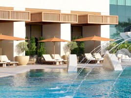 Una piscina al aire libre, sombrillas, sillones reclinables de piscina