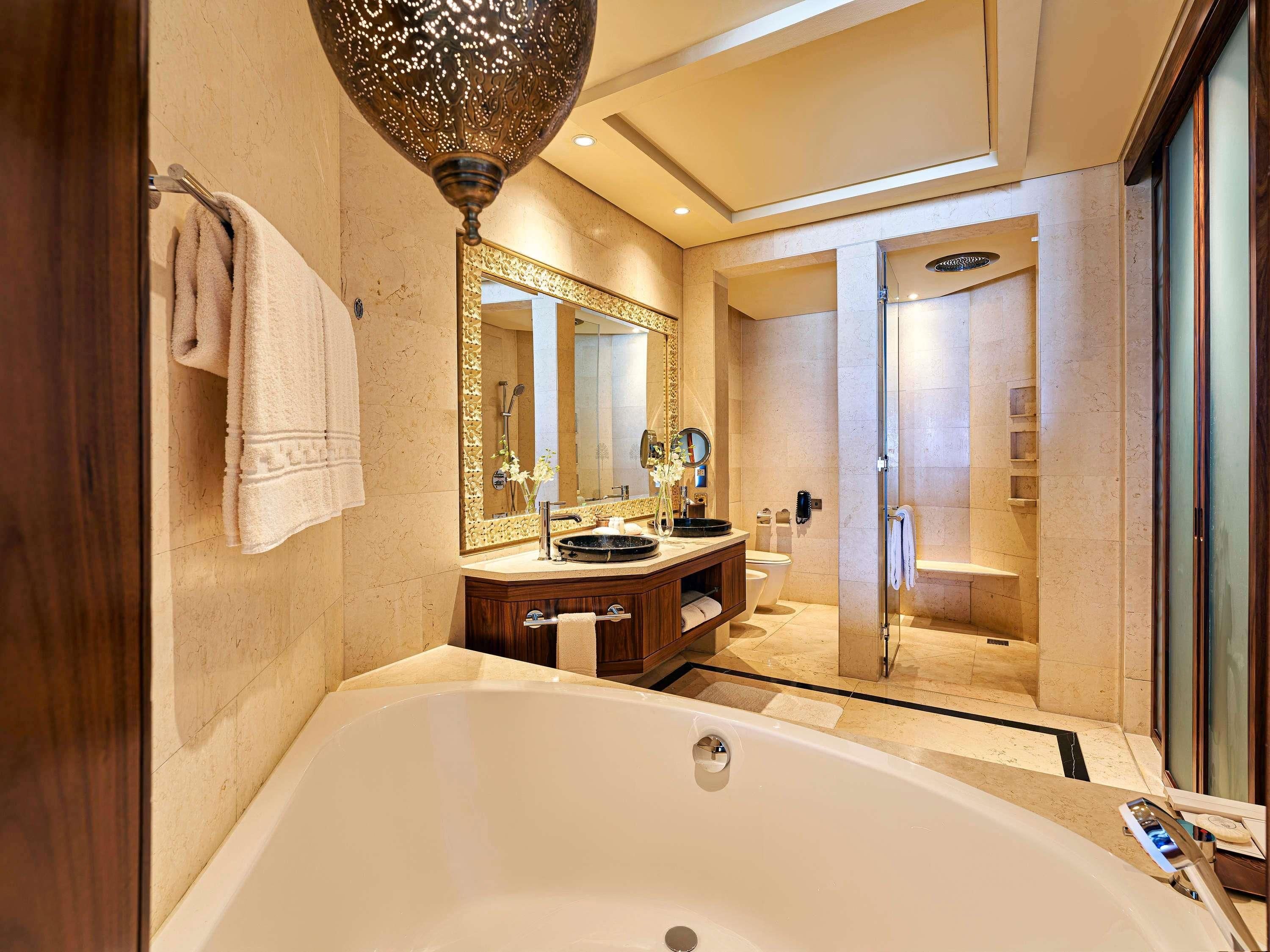 A modern bathroom with a large bathtub, a vanity with a mirror, and a shower area.