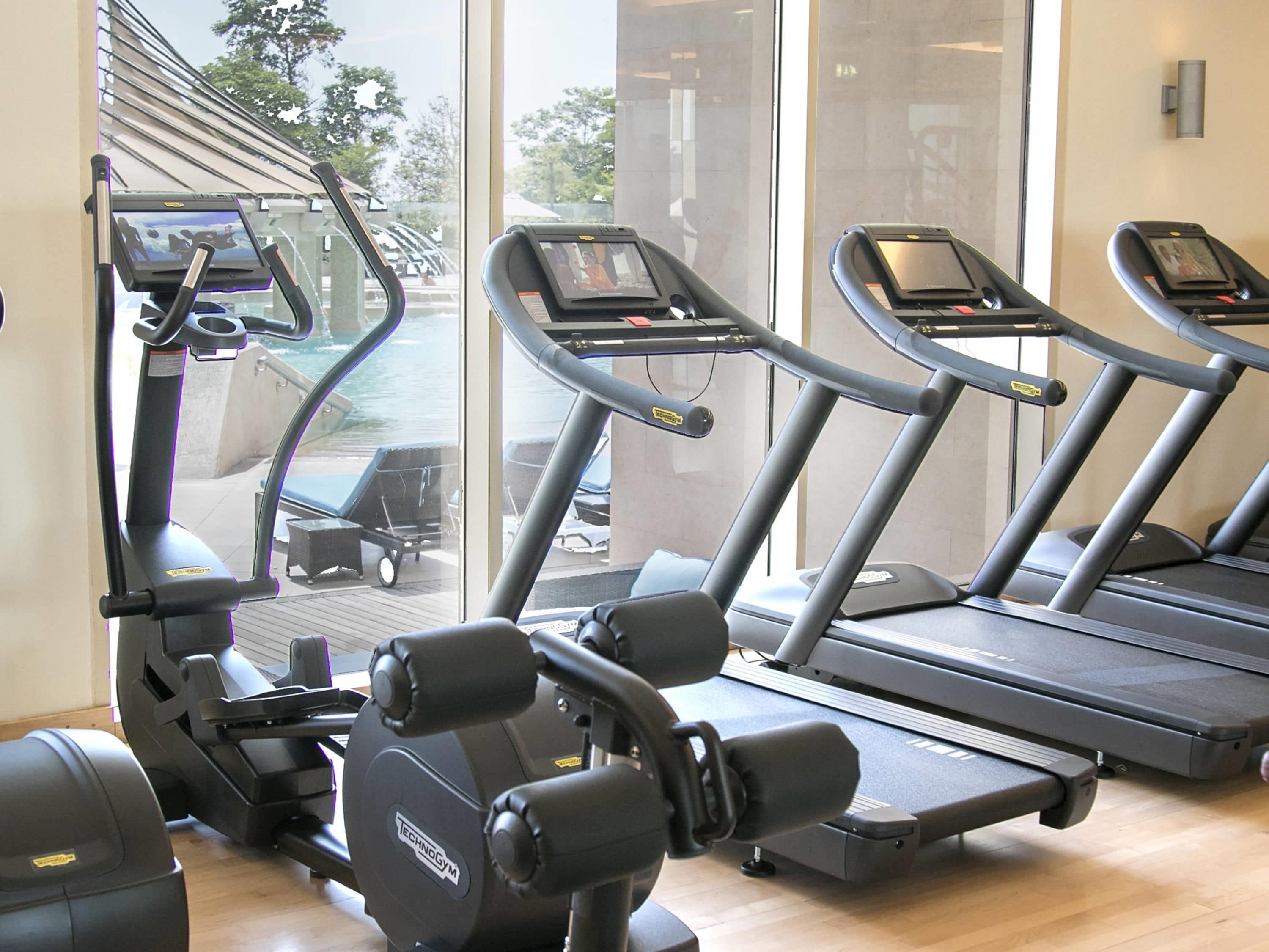 Ein Fitnessraum mit Laufbändern, einem Rudergerät und einer Gewichtbank.