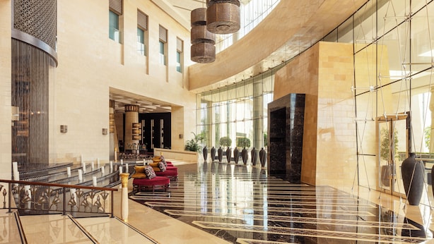A spacious lobby with a curved ceiling, a marble floor, and a seating area with red sofas.