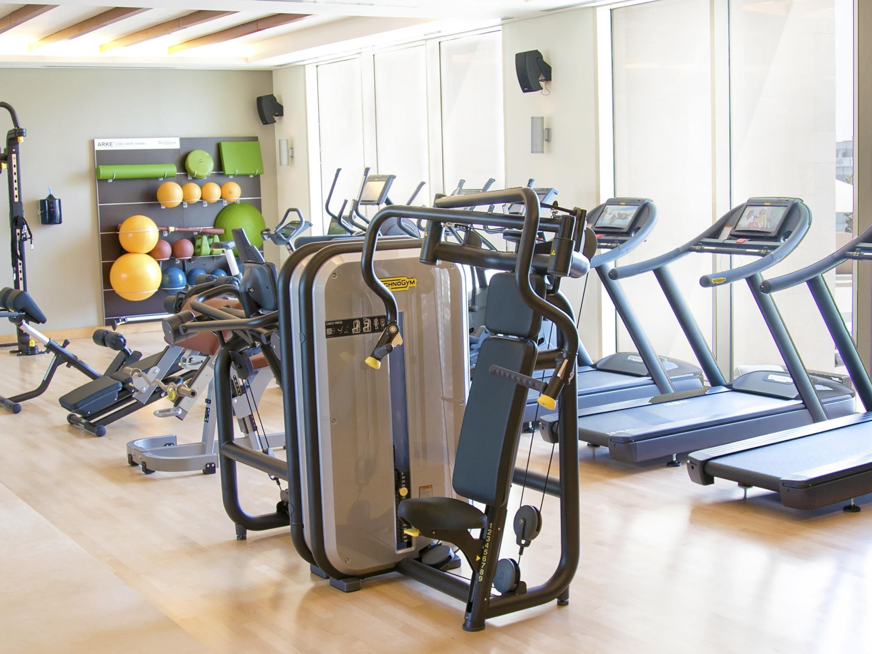 A gym with cardio machines, weight training equipment, and exercise balls.