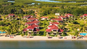 A resort with multiple red-roofed buildings, a beach, and a large body of water. - Hopkins Bay Belize, a Muy'Ono Resort (Hopkins)