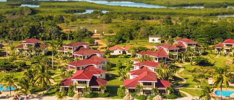 A resort with multiple red-roofed buildings, a beach, and a large body of water.