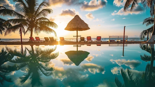A beach scene with a pool, lounge chairs, and a thatched umbrella. - Hopkins Bay Belize, a Muy'Ono Resort (Hopkins)