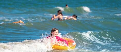 A person on a yellow inflatable in the ocean with waves.