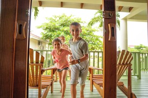 A wooden deck with outdoor seating and a view of a house in the background.