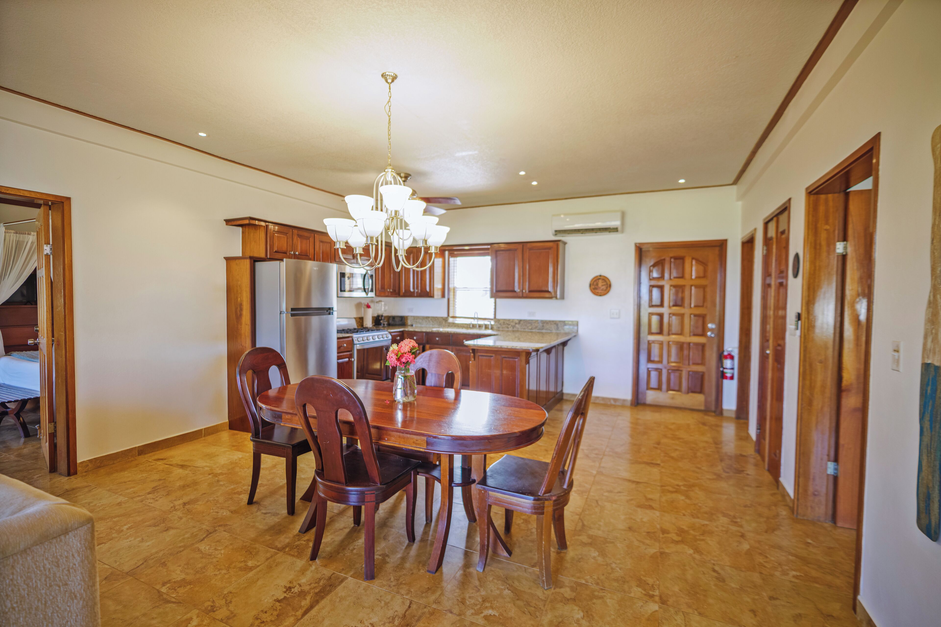A spacious kitchen with wooden cabinets, a central island, and a chandelier.