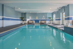 Une piscine intérieure avec un sol carrelé, des bancs et des panneaux de signalisation de sécurité.
