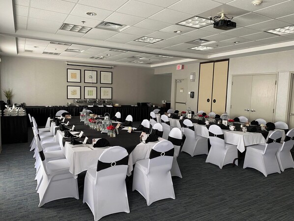 A conference room with rows of tables and chairs, a projector, and framed pictures on the wall. - Holiday Inn Express & Suites Belleville by IHG (Belleville)