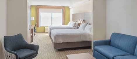 A hotel room with a bed, two chairs, a sofa, a wooden table, and a window with a view.