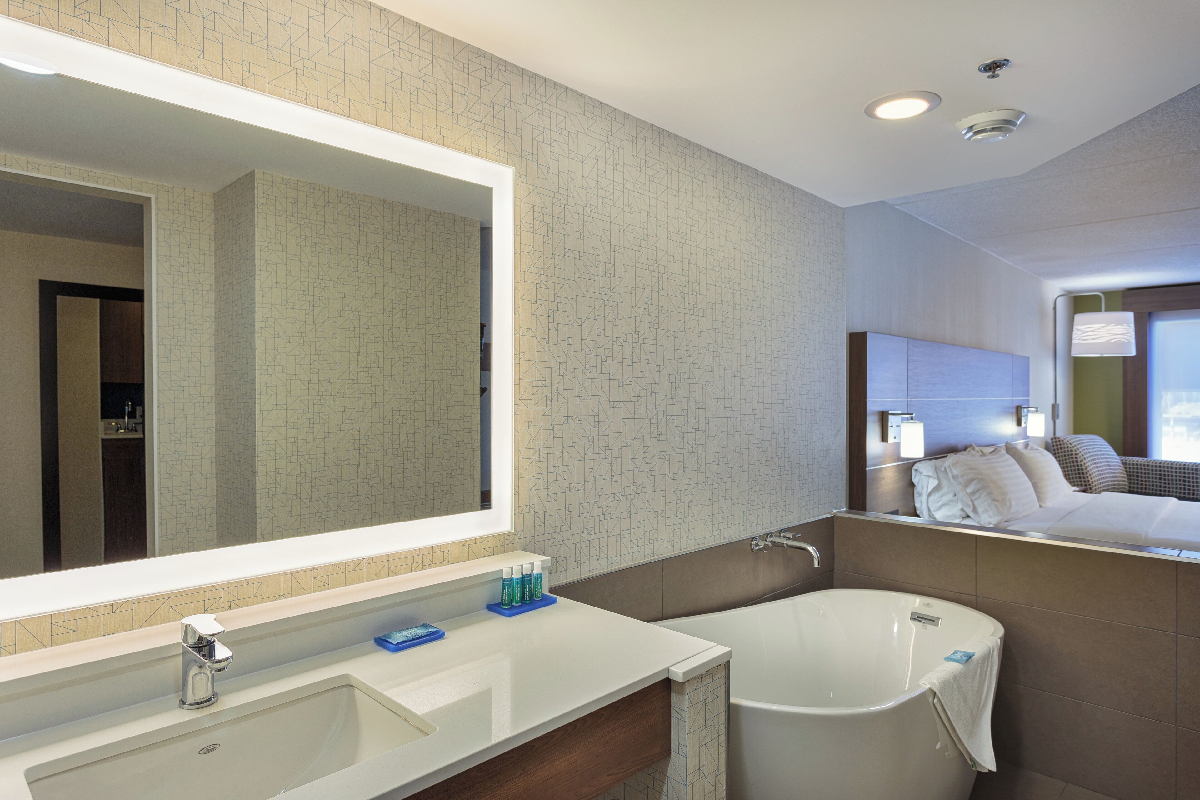 Un baño moderno con un espejo grande, una bañera y un tocador con lavamanos.