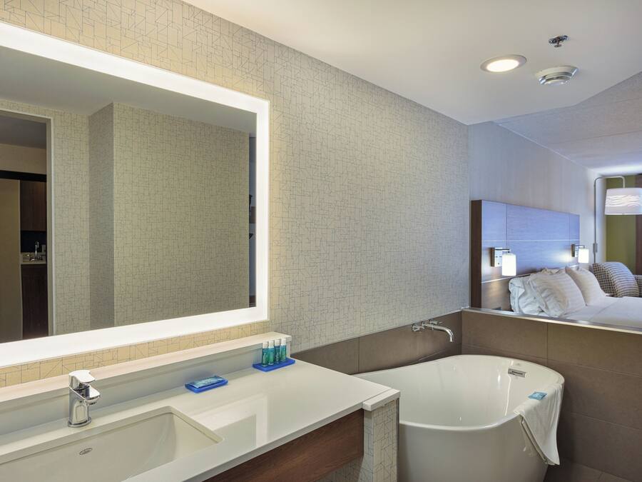 Un baño moderno con un espejo grande, una bañera y un tocador con lavamanos.